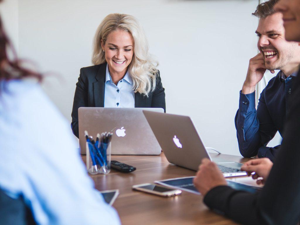 Arbetsmöte, glada personer med laptops vid ett bord